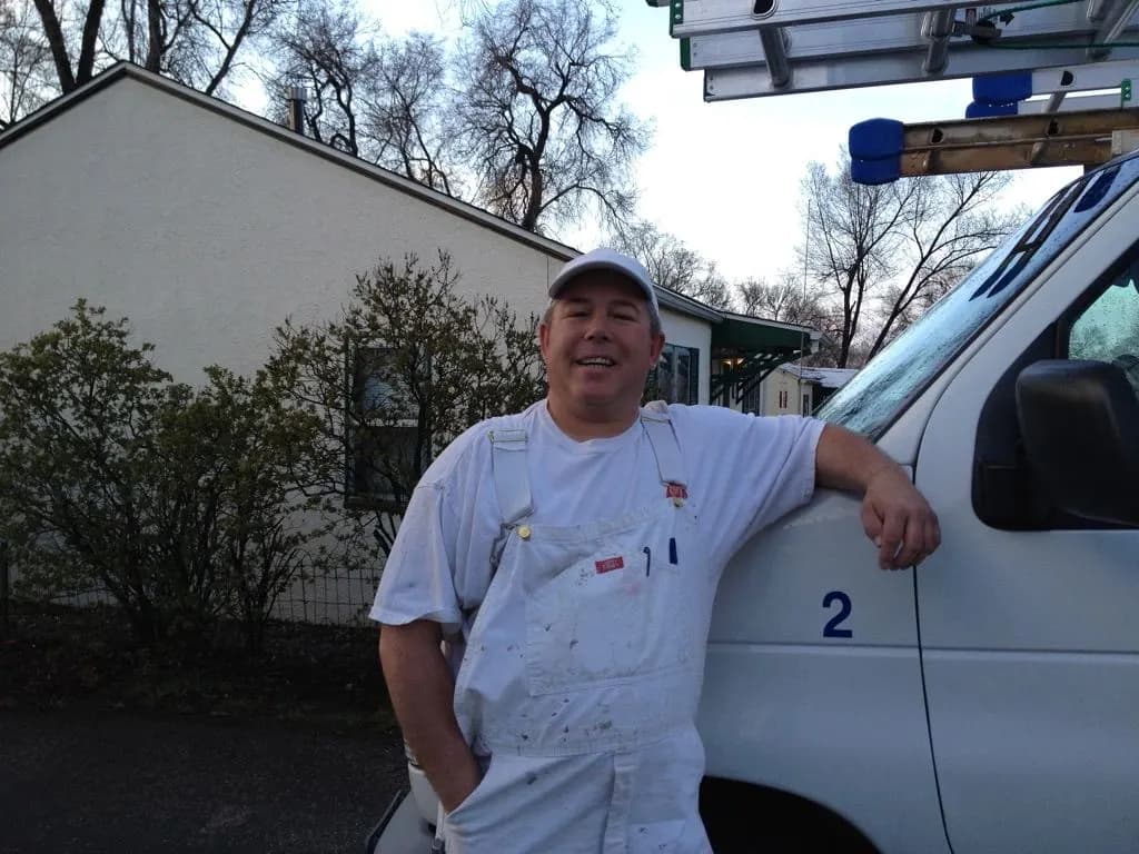 Dave Shipler, owner of Brush Masters, in painter's whites beside his work van