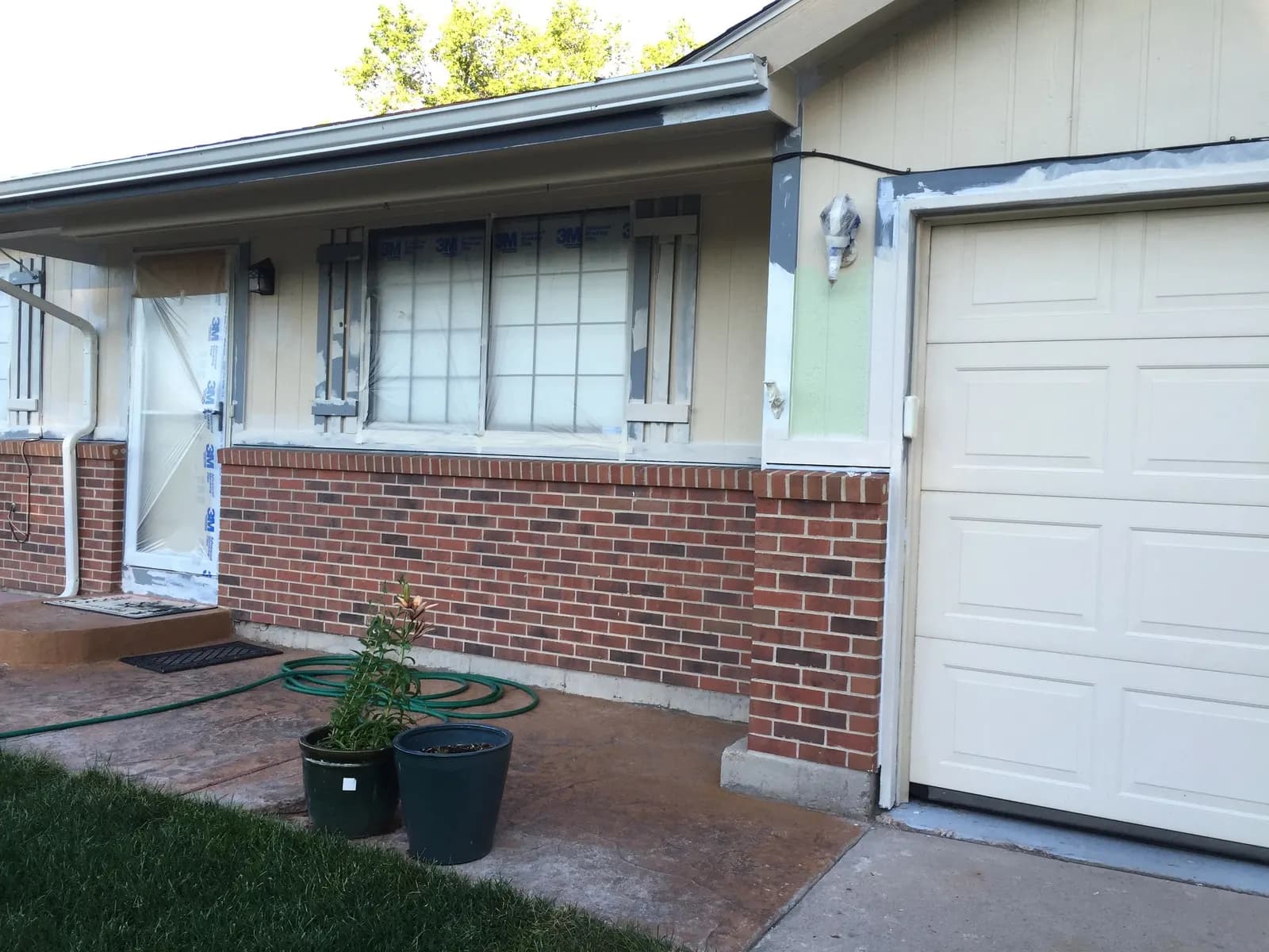 Brick ranch with new siding and trim primed around the window and garage, mid-project